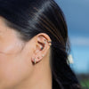 Close-up of an ear with multiple earrings against a blurred natural background